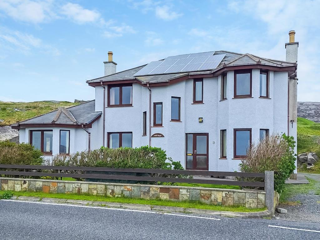 a white house with solar panels on the roof at Sealladh Lingeigh in Pollachar
