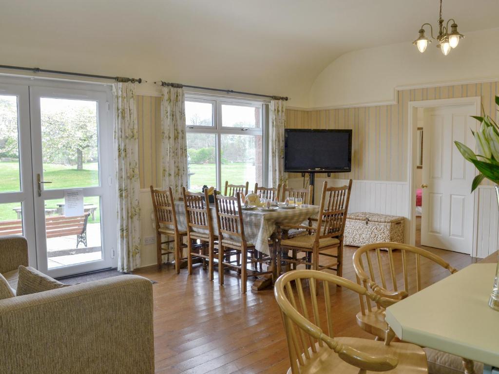 a living room with a table and chairs and a television at Kinnelhook Holiday Cottage in Templand