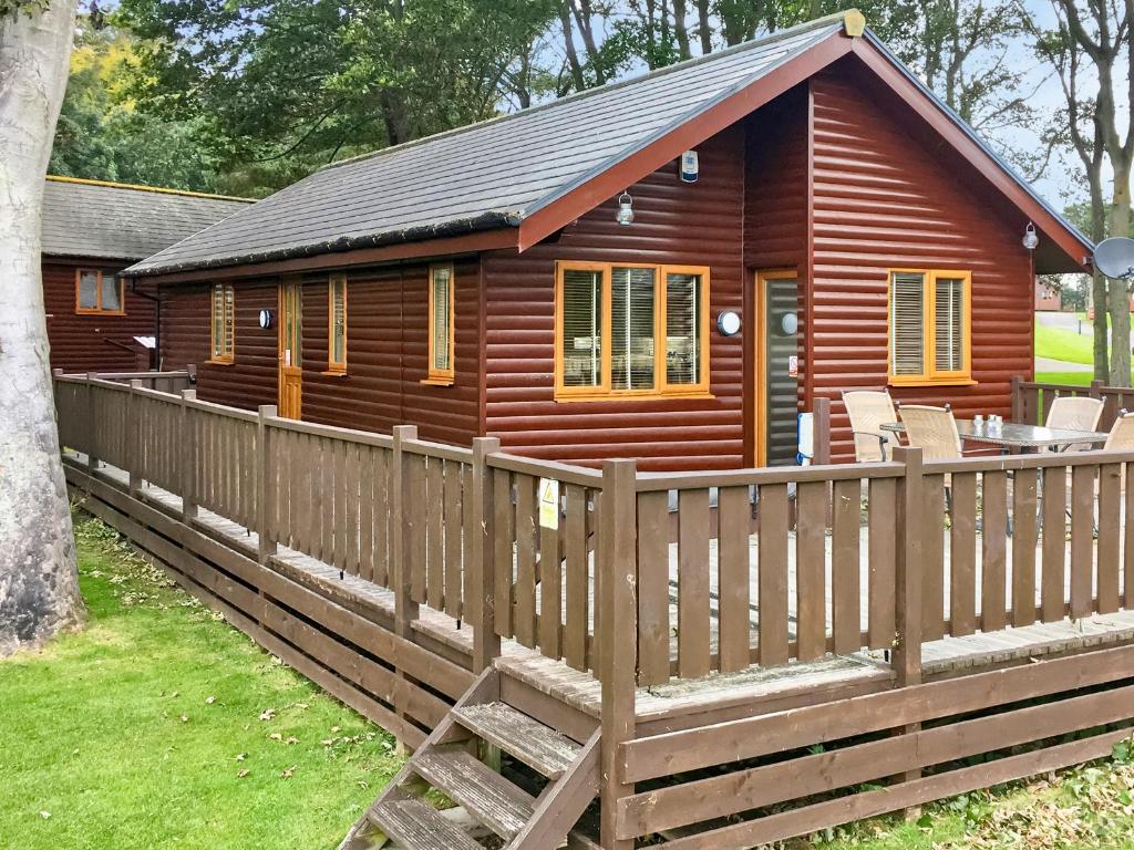 a wooden cabin with a fence in front of it at Sycamore Lodge in Sewerby