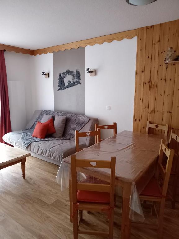 a living room with a table and a couch at Résidence les églantines in Le Mélézet