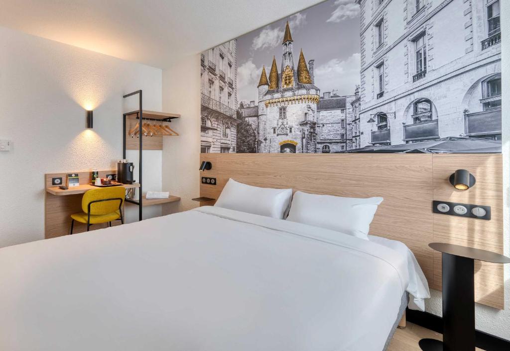 a hotel room with a white bed and a building at B&B HOTEL Bordeaux Mérignac Cadera Aéroport in Mérignac