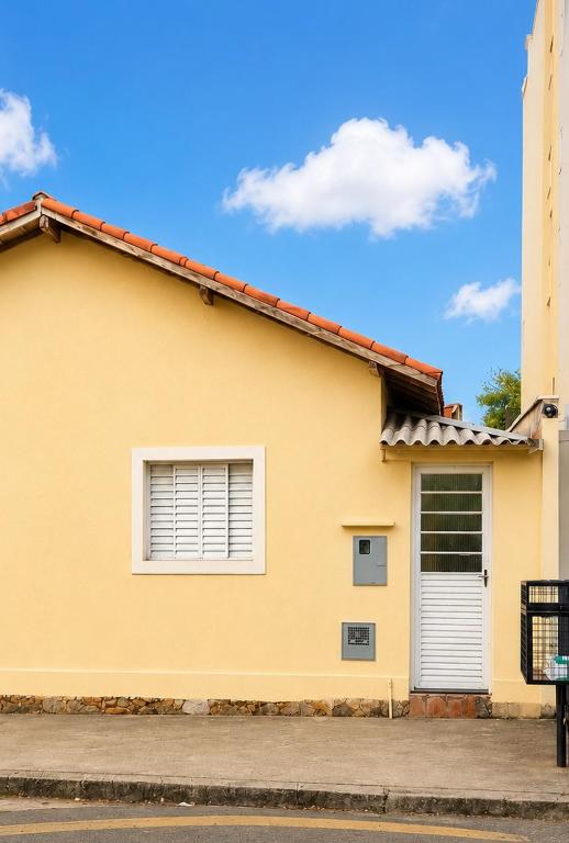 a yellow house with two windows on a street at Casa no centro de Poços de Caldas in Poços de Caldas
