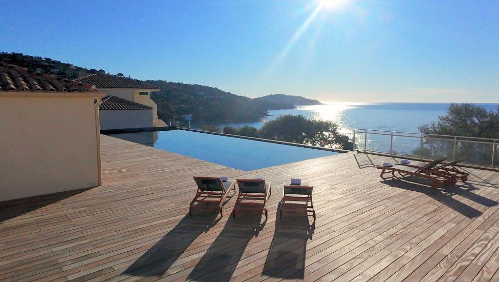 two chairs on a deck with a view of the water at Hôtel-Club du Domaine d'Aiguebelle, USSIM Vacances in Le Lavandou
