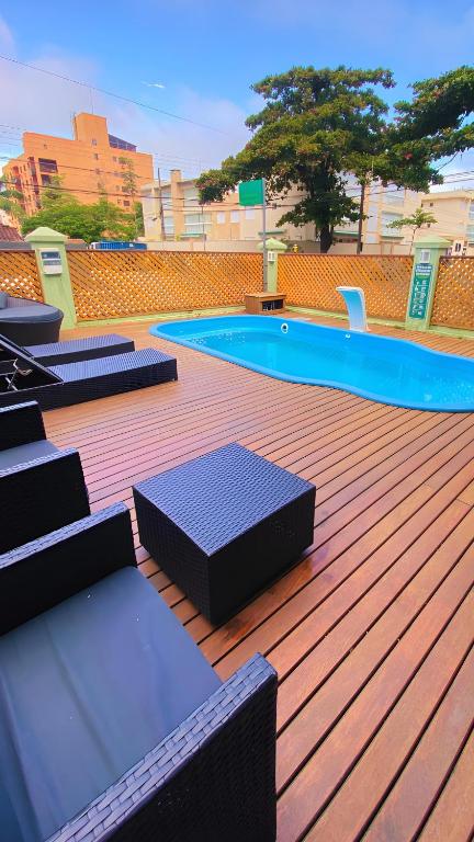 a wooden deck with benches and a swimming pool at Pousada Nosso Lar - Opte sem ou com Café, Estacionamento e a uma Quadra da Praia in Guarujá