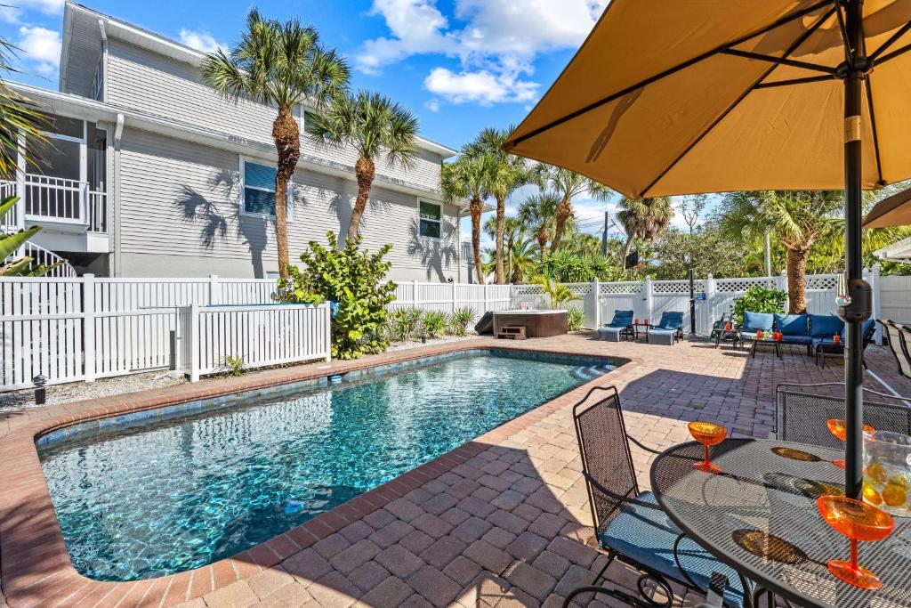 a swimming pool with a table and an umbrella at Siesta SunDaze - 5430 in Sarasota