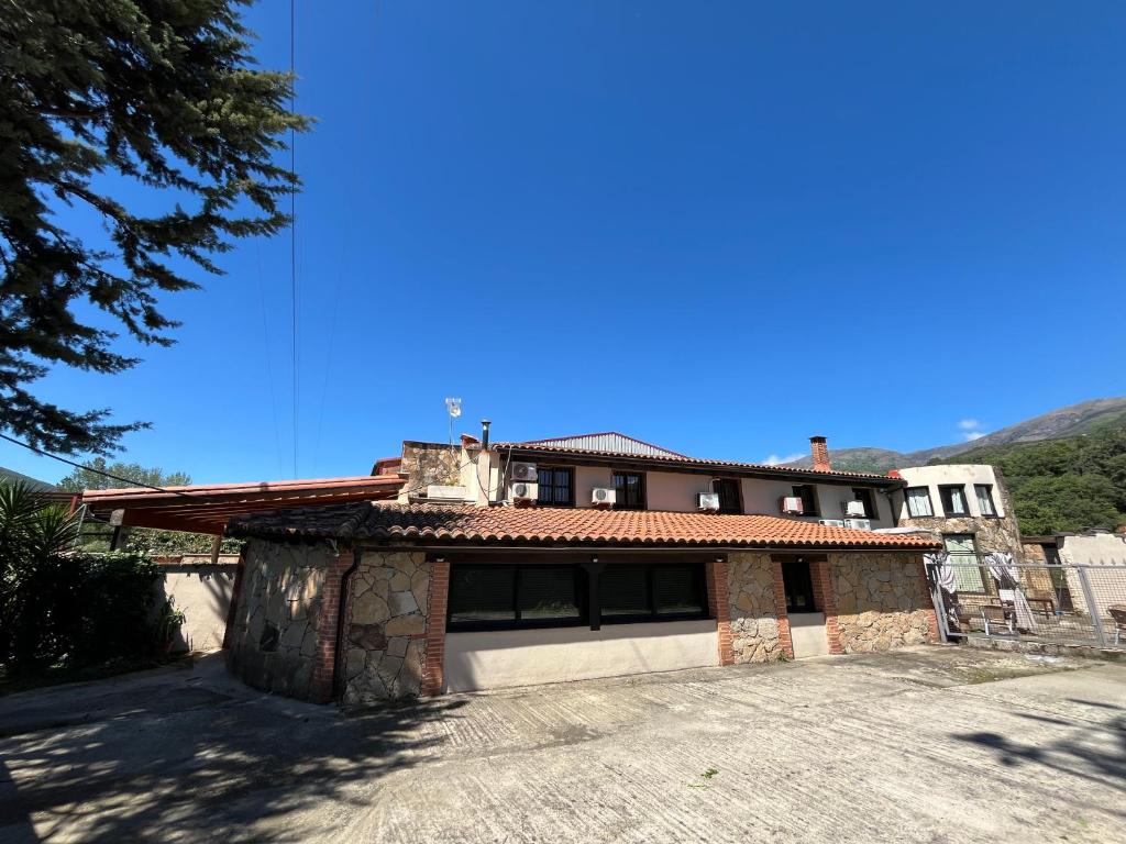 a house with a stone building with a sky background at Casa Rural Valle del Jerte in Jerte