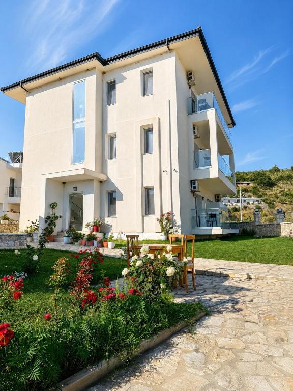 a house with a table and chairs in front of it at SEA & LAKE VIEW VILLA in (( Kalive Gjoka ))