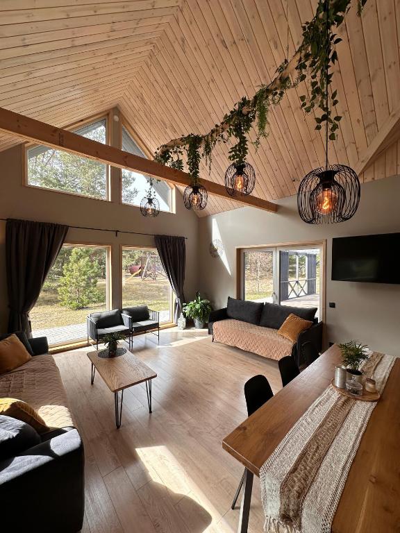 a living room with a wooden ceiling and a table at Jūrmalciema Pērle AMBER in Jūrmalciems