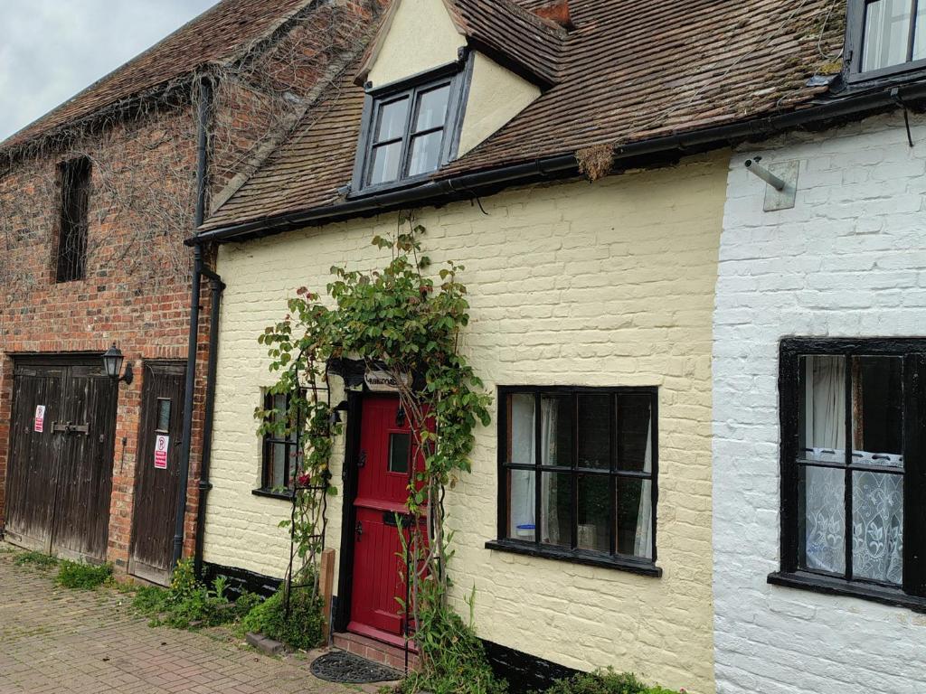 an old white house with a red door and vines at Runnymede in Tewkesbury