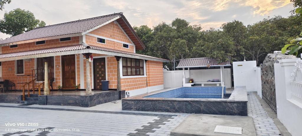 a brick house with a pool in front of it at Vriksha Heritage Farm Stays in Sethumadai