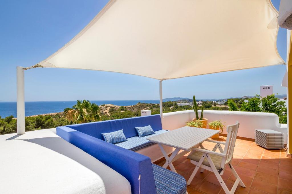 a balcony with a blue couch and a table at Can Panorama in Talamanca