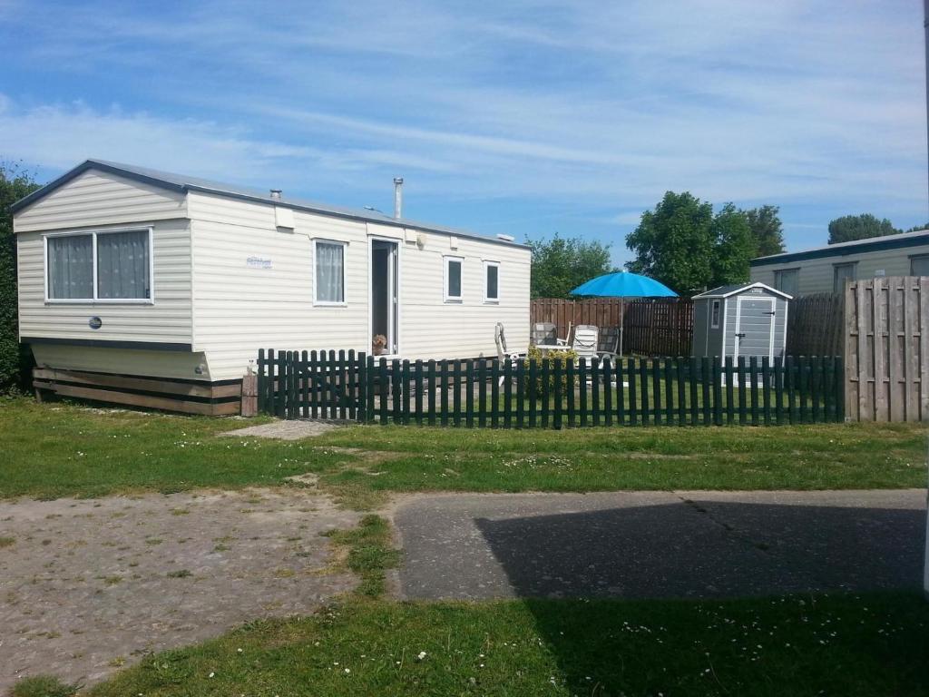 a white house with a fence in a yard at VZ779 Stacaravan in Wemeldinge in Wemeldinge