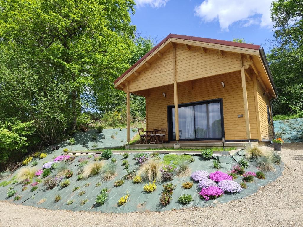 a small house with flowers in front of it at Cabane des Roches à 2 min de Vulcania - Calme et Nature in Saint-Ours