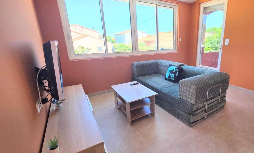 a living room with a couch and a table at LE BARCARES Logement "Marenda" climatisé avec terrasse, plage à pied, place de parking - 4 personnes in Le Barcarès