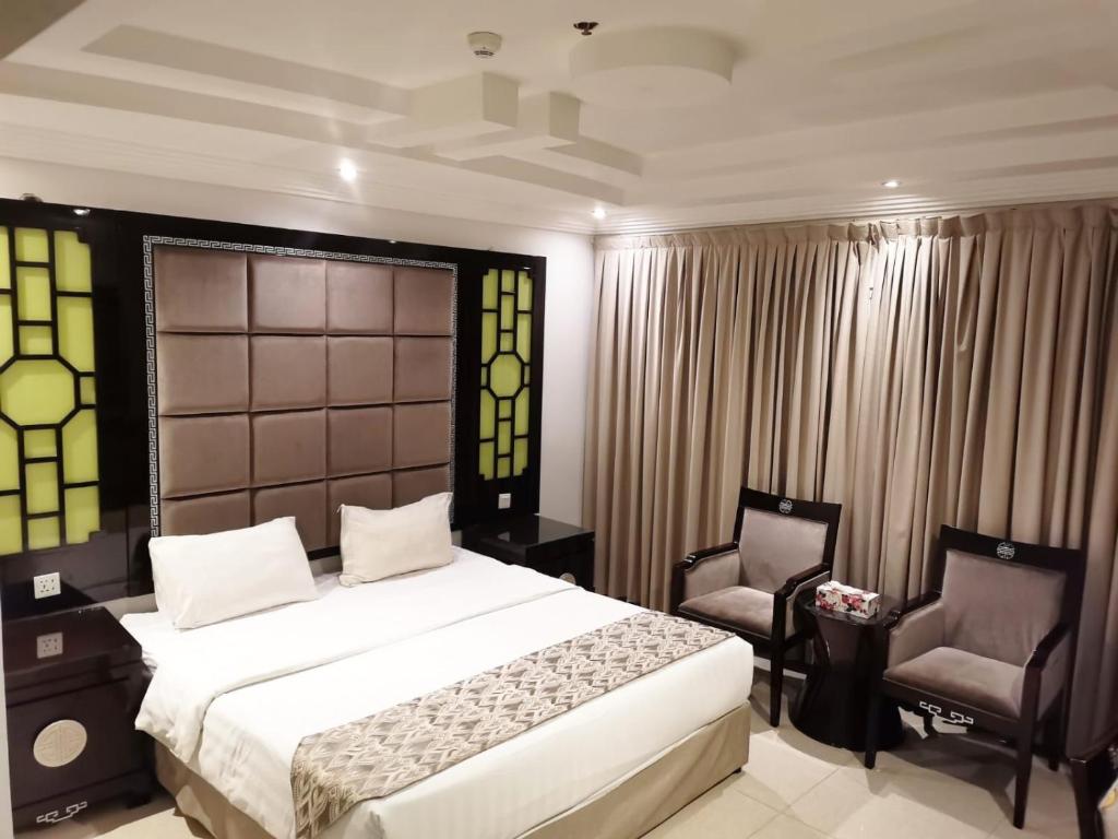 a bedroom with a large bed and two chairs at جولدن نيو الدار للشقق المخدومة in Jazan