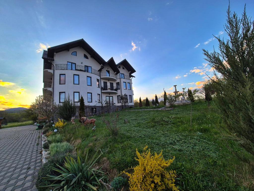a large white house on top of a hill at Pensiunea Vraja in Giuleşti