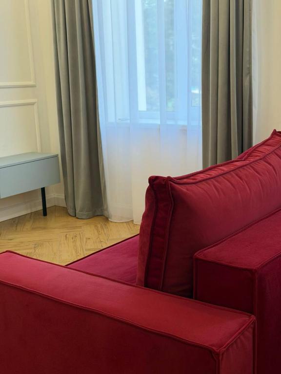 a red couch in a living room with a window at Green door in Kolomiya