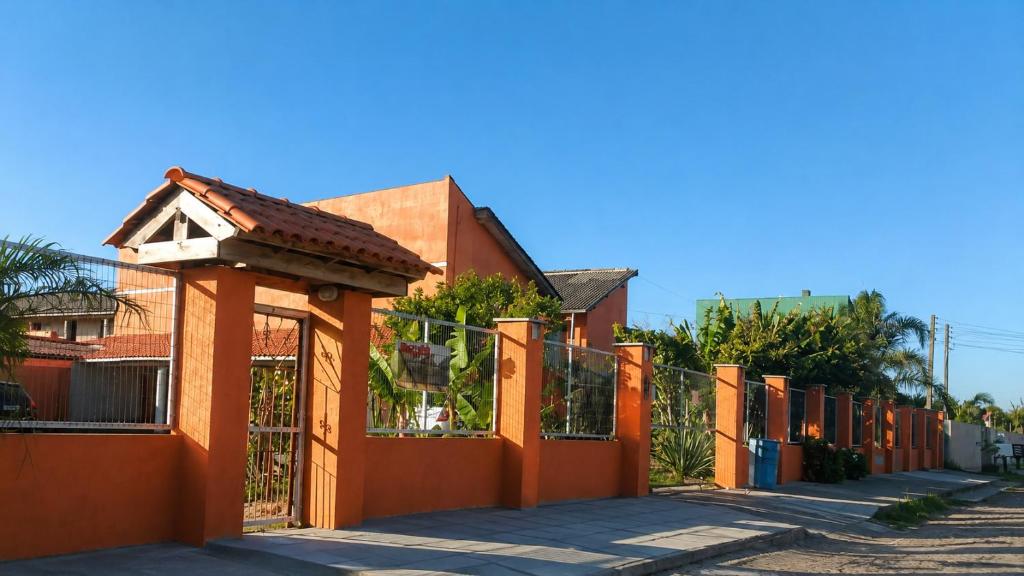 an orange fence with a house with a roof at Pousada laranja in Xangri-lá