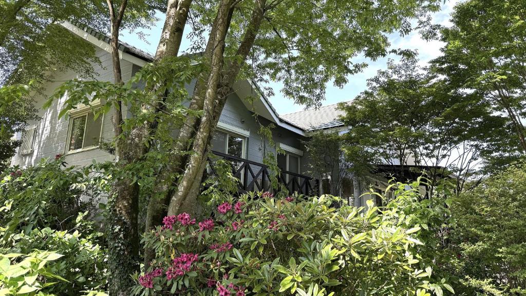 a white house with flowers in front of it at Garden Villa Minamiaso in Minami Aso