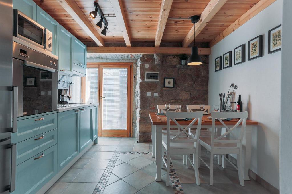 una cocina con armarios azules y una mesa con sillas en Charming old stone house, en Sali