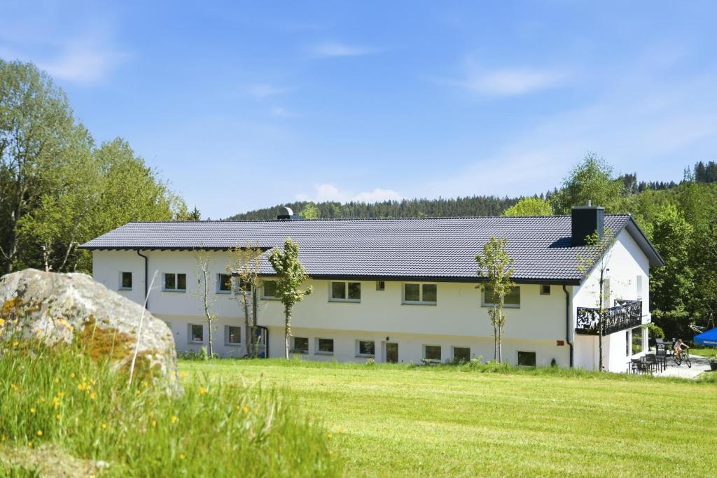 a large white building with a grass field at Schwarzwald Ledi - Bed & Breakfast Feldberg in Feldberg