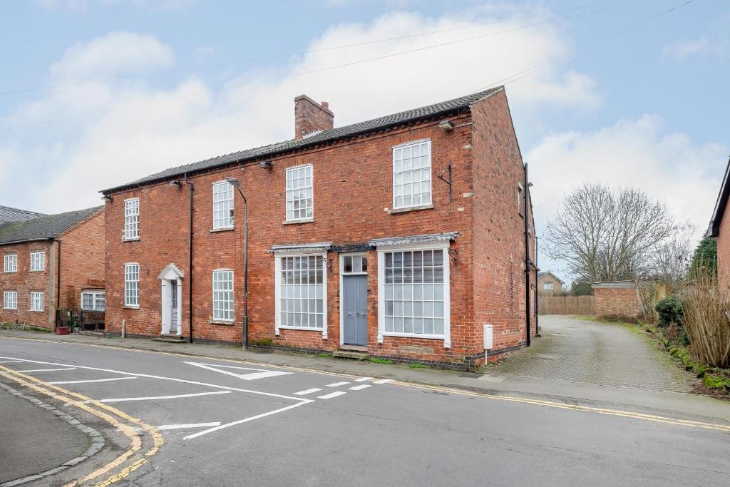 a red brick building with white windows on a street at Hambleton House in Castle Donington