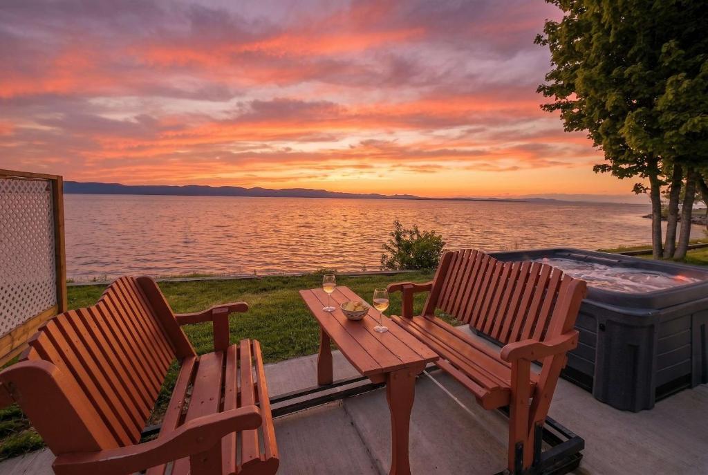 two chairs and a table on a deck next to a hot tub at Chalet #8 Waterfront with Spa, Fireplace, Wifi and AC in Cap-Saint-Ignace