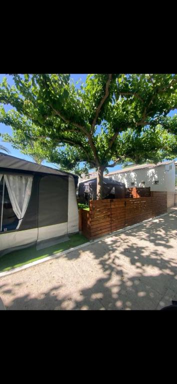 a house with a fence and a large tree at Caravana Camping Coelius in Miramar