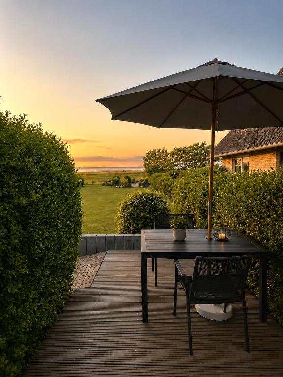 a table and chair with an umbrella on a deck at Bungalow Seeblick Am Achterwasser in Ueckeritz