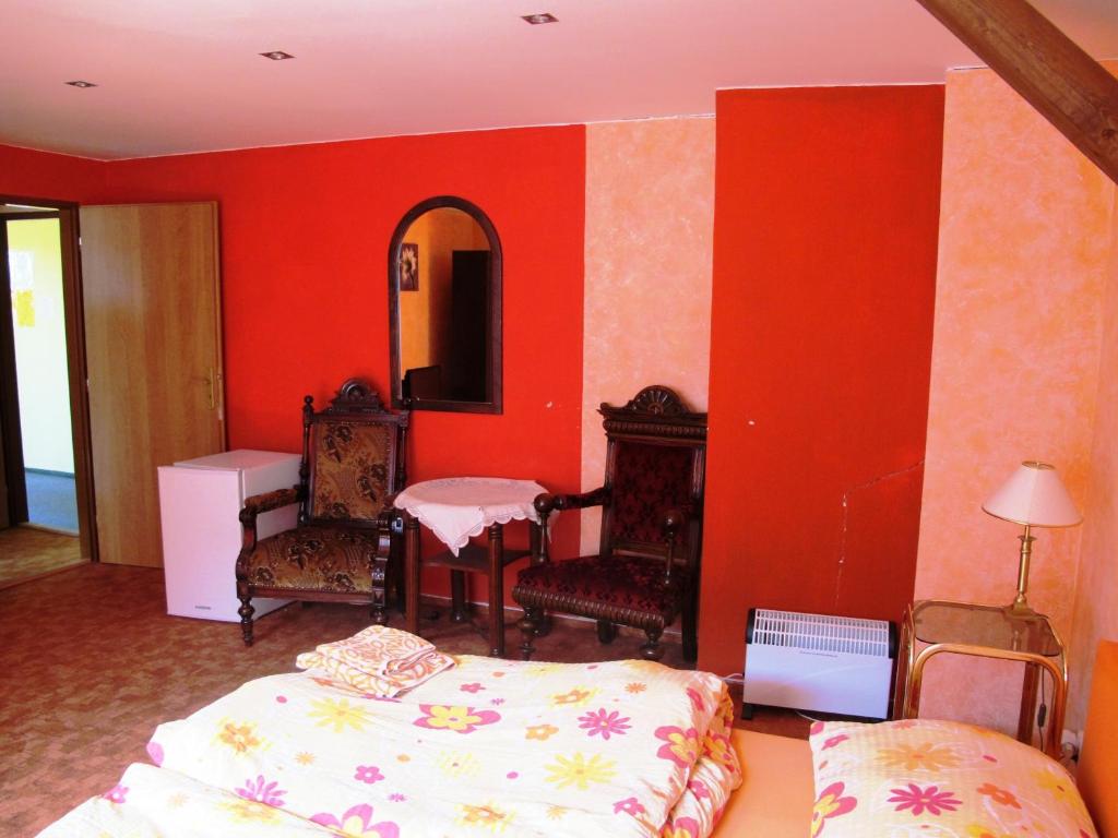 Schlafzimmer mit roten Wänden, einem Bett und einem Spiegel in der Unterkunft Hotel U Lišky in Hošťka