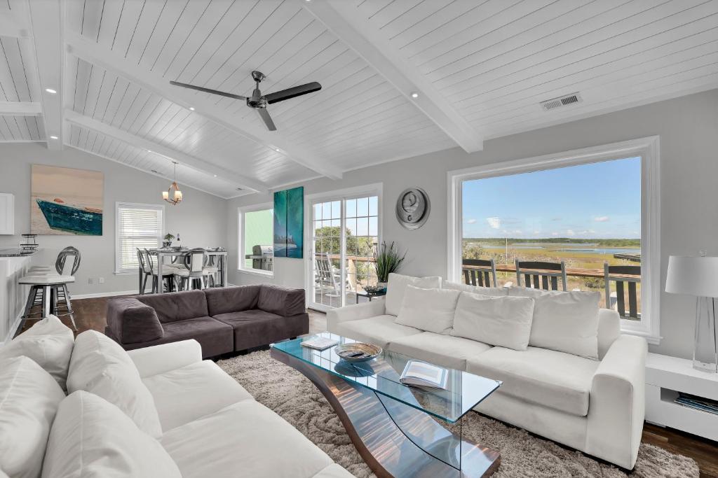 a living room with a white couch and a table at All Marshed Up-Stunning Water View 1 block to beach in Surf City