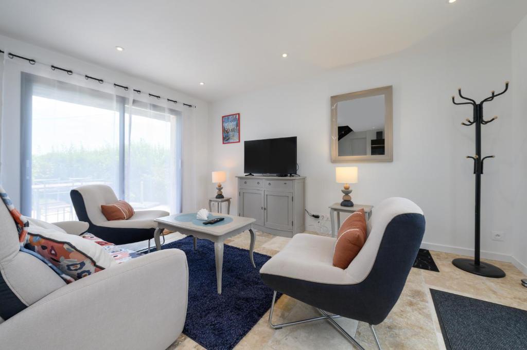 a living room with two chairs and a tv at Ker Marin -Maison Refuge Des Marées in Sarzeau