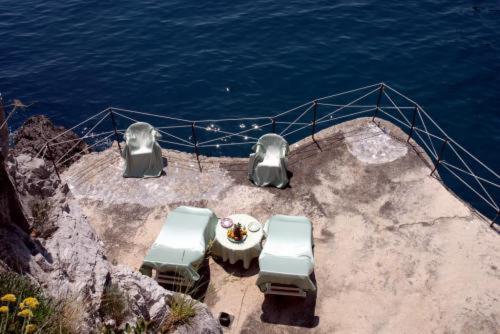 a table and chairs on a boat near the water at Albergo La Conca Azzurra in Conca dei Marini