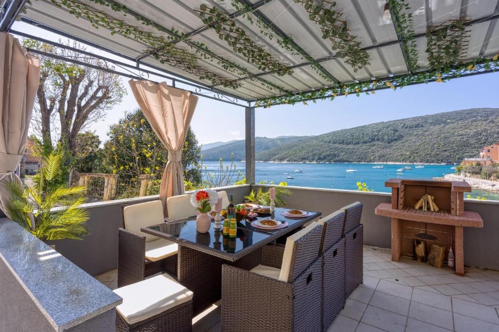 a patio with a table and chairs and a view of the water at Riva Luxury Seafront in Rabac