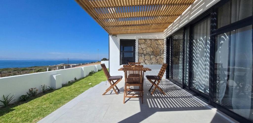 a patio with a table and chairs on a balcony at Sky & Sea in St. Helena Bay