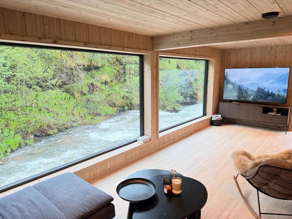 a living room with large windows and a river at By the River in Vinje