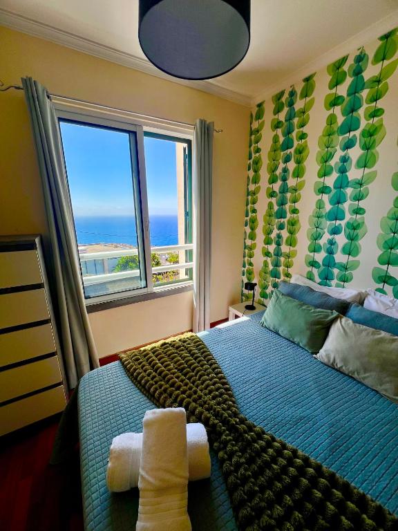 a bedroom with a bed with a view of the ocean at Caniço Lodge in Caniço