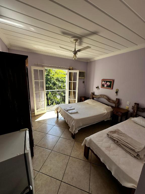 a room with two beds and a window at Flats D'amoras em Conservatória sem café da manhã in Conservatória