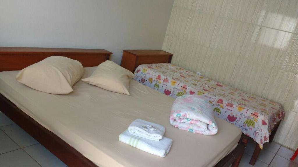 een bed met twee handdoeken en twee kussens erop bij Pousada JM in Parque Dom Bosco