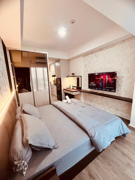 a bedroom with a large bed with a tv on the wall at P4 Type Studio Apt Swimming Pool View Batam Centre in Batam Center