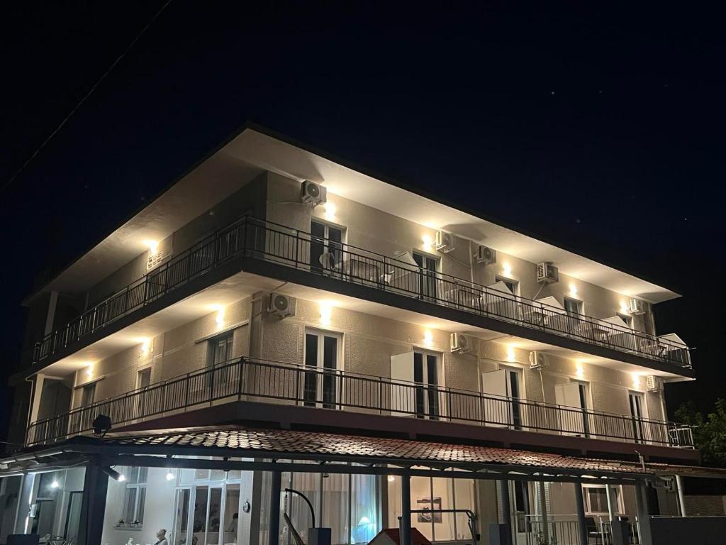a large white building with a balcony at night at Golden Beach Sea View in Nea Mesangala