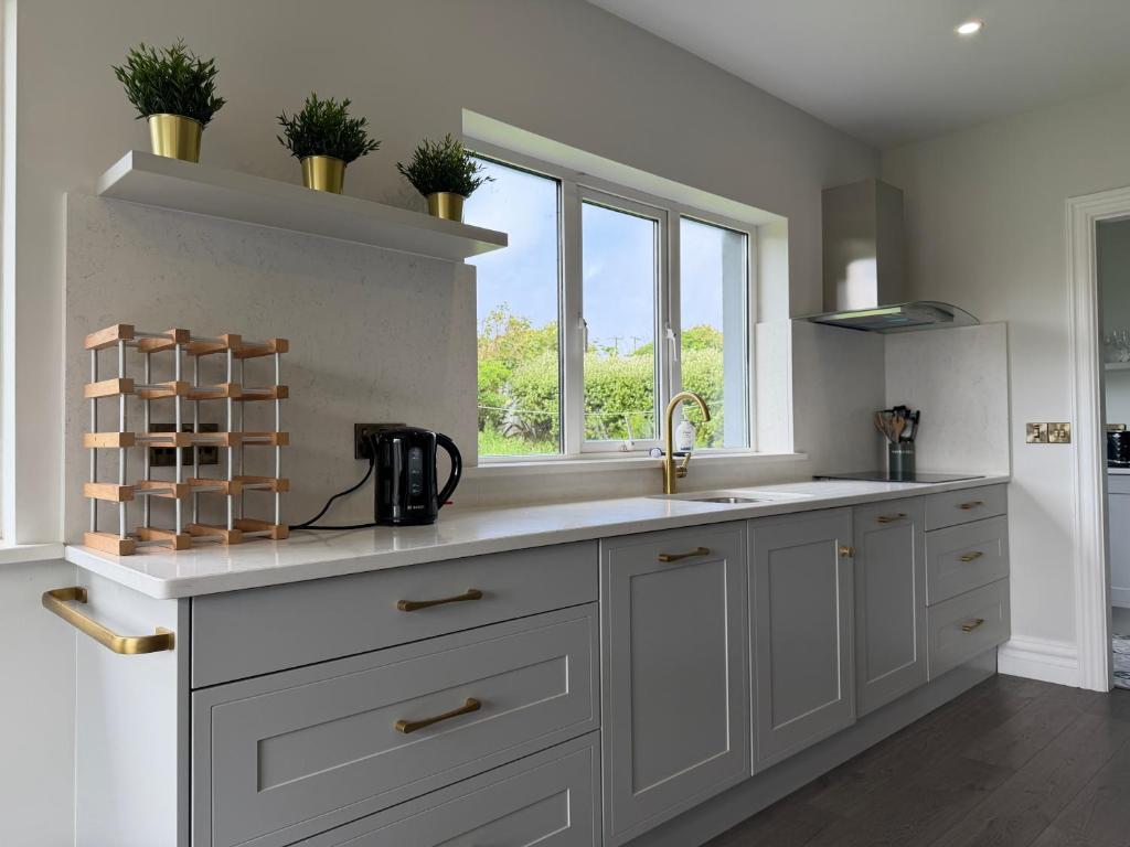 a white kitchen with a sink and a window at Number 6 Westpark Spanish Point in Spanish Point