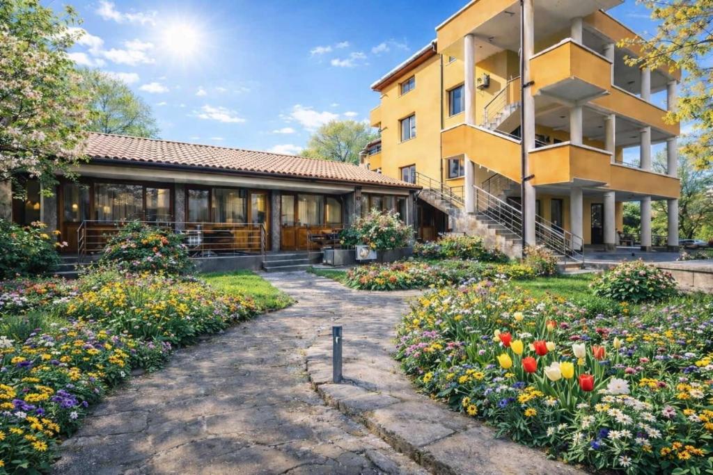 a building with a garden of flowers in front of it at Вила Стряма in Hisarya