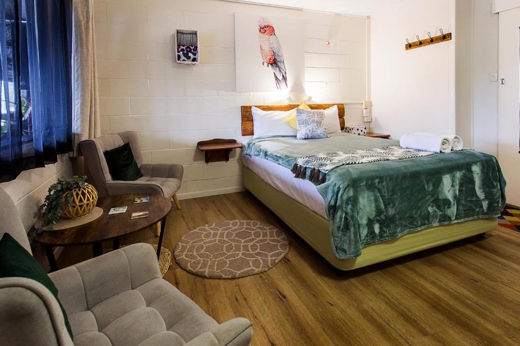a bedroom with a large bed and a chair at Kilcoy Motel in Kilcoy