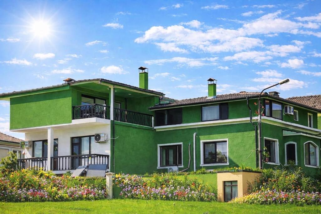 a green and white house with flowers in front of it at Зелената къща in Hisarya