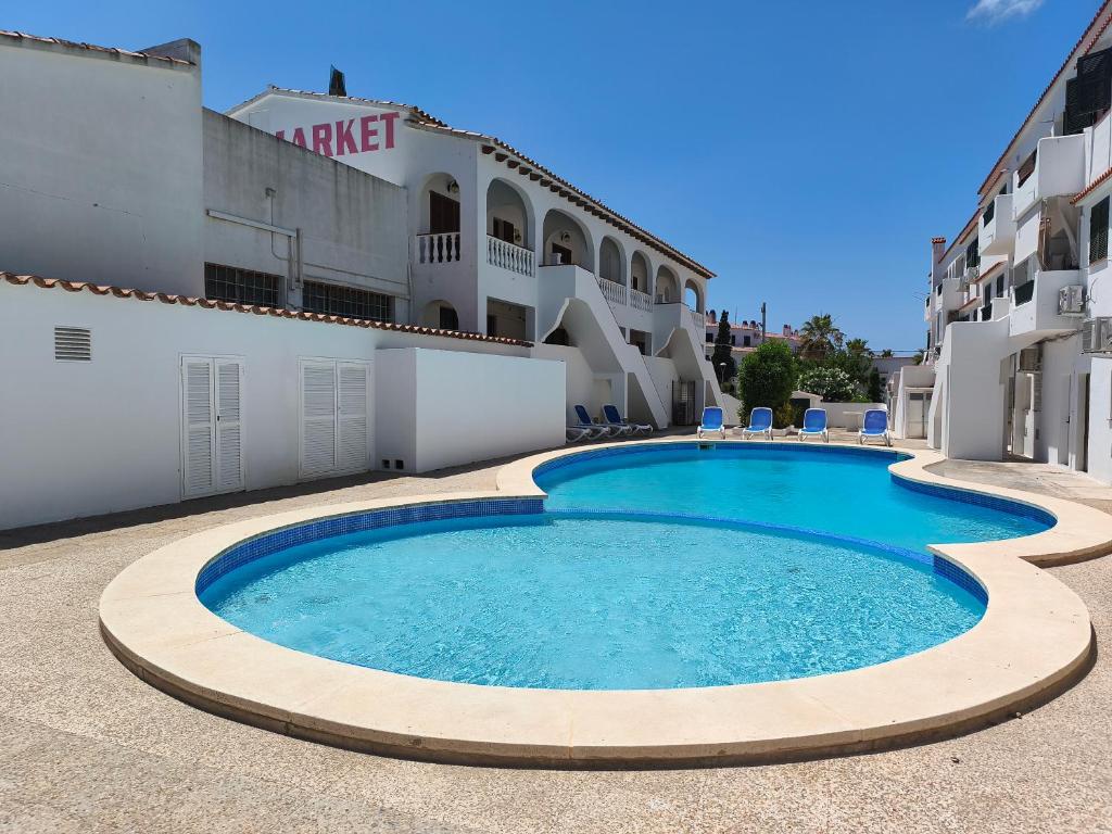 a large swimming pool in front of a building at Apartamentos Xoroi in Cala en Porter