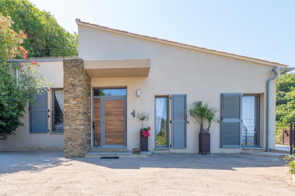 a white house with blue shutters on it at U Scogliu Escale De Rêve in Poggio-dʼOletta