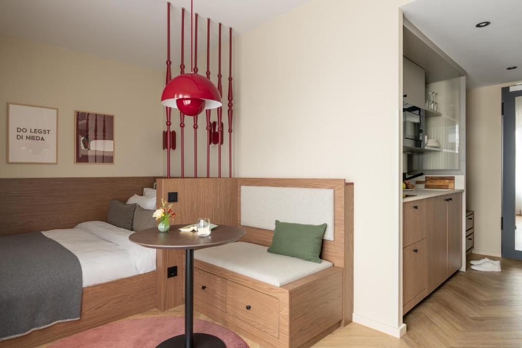 a bedroom with a bed and a table and a kitchen at Bob W Munich City West in Munich