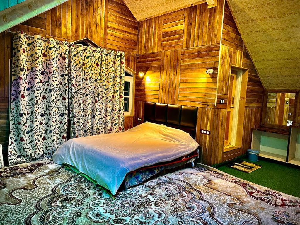 a bedroom with a bed in a room with wooden walls at The Riverside Lodge Gulmarg in Gulmarg