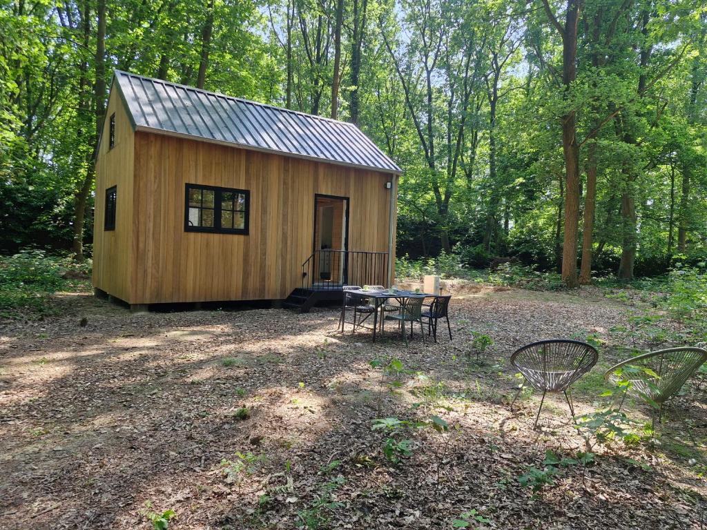 a small wooden cabin in the woods with a table and chairs at In het sprookjesbos in Zonnebeke